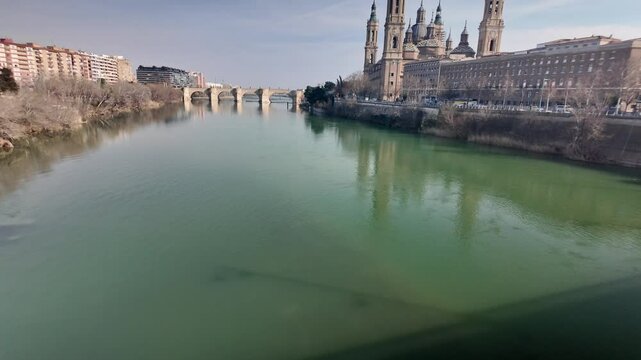 Green waters of ebro river flowing in zaragoza with basilica del pilar majestically standing on riverbank