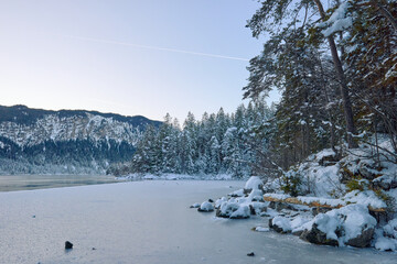 Breathtaking Alpine Winter Wonderland: Majestic Zugspitze Mountain Reflects in Frozen Eibsee Lake Amidst Snowy German Landscape Picturesque Ski Resort Nestled in Bavarian Forest
