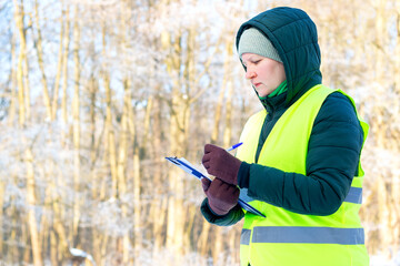 Female ecologist inspects trees. Eco volunteer. Forestry engineer works in winter. Inspector...