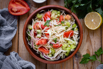 Diet salad with vegetables. Salad with tomatoes, cabbage, celery in a brown plate for breakfast. View from above. Close-up