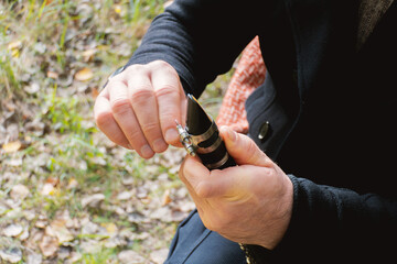 A person's hands assembling a clarinet reed and mouthpiece.