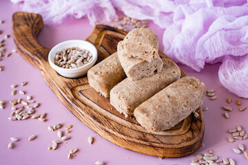 Homemade halva on a wooden board on a pink background. Sweet dessert: sweet halva for breakfast. Close-up