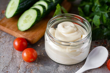Thick mayonnaise in a jar on a gray background. Homemade mayonnaise for lunch in a glass jar.