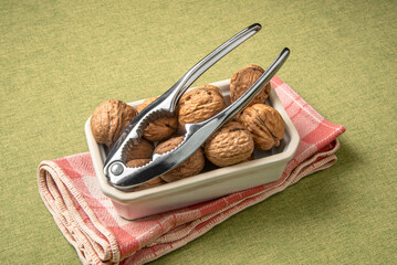 Heap of dry walnuts in a cup, with an iron steel nutcracker