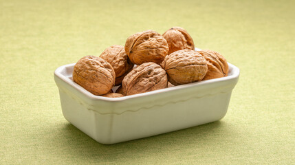 Heap of dry walnuts in a cup, on a table
