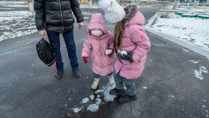 Grandfather walks with his granddaughters after school in the park in sunny winter day