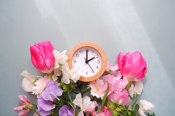 Spring forward background. Beautiful flowers and a clock composition on pastel color background. Spring image and floral background.