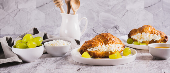Delicious croissant with cottage cheese and grapes on a plate on the table web banner
