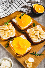 Sandwiches with ricotta, orange and banana on a board on a table vertical view