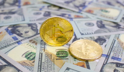 Close up of metal golden bitcoin crypto currency coins on US 100 dollar bills. Bitcoin coin and cash background