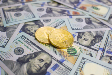 Close up of metal golden bitcoin crypto currency coins on US 100 dollar bills. Bitcoin coin and cash background