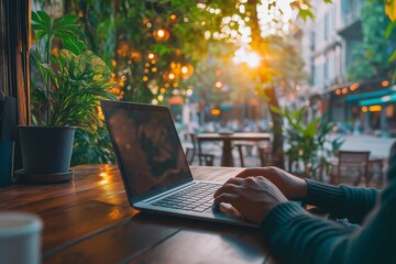 A man with a laptop in an outdoor cafe surrounded by greenery. The concept of freelancing and remote work.