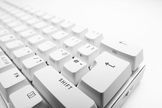 White, wireless gaming mechanical computer  keyboard. Closeup on the enter key, keycap. Minimal, modern design on white background. 60 percent keyboard. copy space.