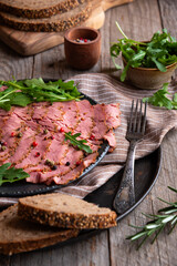 Sliced pastrami meat with rosemary and pepper