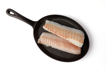 two fresh cod fish fillets on black cast iron frying pan isolated on white background. top view with copy space