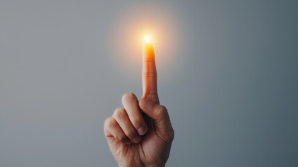 Close up of a human hand with the index finger pointing upwards illuminated by a bright focused light symbolizing creative realization