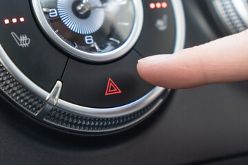 Car Interior Controls Activating the Hazard Lights for Enhanced Safety and Alertness. a closeup of a car dashboard where a finger is pressing the hazard light button
