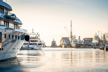 Sunset photo of large superyacht Shipyard located in Genova, Italy, with large cranes for ongoing...
