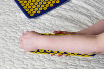 Women's forearm on a needle roller - foot massage using an applicator Kuznetsov, Russia