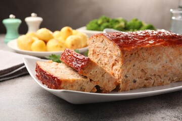 Delicious baked turkey meatloaf with vegetables served on grey table, closeup