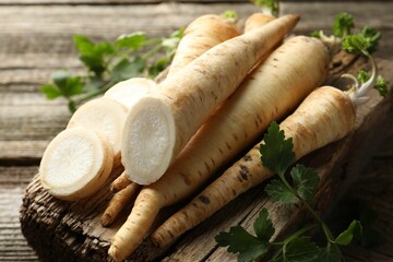 Parsley roots and leaves on wooden table, closeup