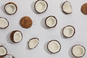 Pieces of cracked coconuts on light background, flat lay