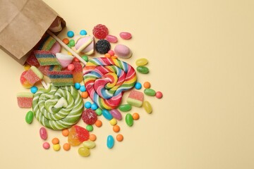 Different delicious candies and marshmallows on beige background, top view. Space for text