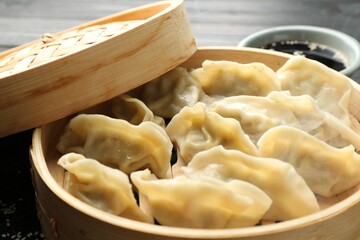 Tasty boiled gyoza (dumplings) in bamboo steamer on table, closeup