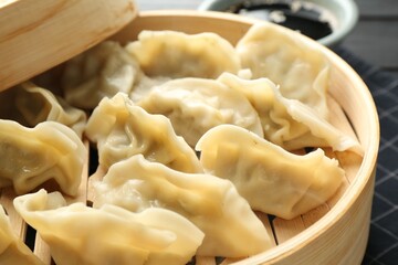 Tasty boiled gyoza (dumplings) in bamboo steamer on table, closeup