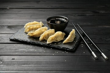 Tasty boiled gyoza (dumplings) served on black wooden table