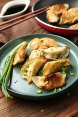 Tasty fried gyoza (dumplings) on wooden table, closeup