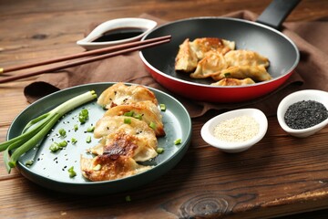 Tasty fried gyoza (dumplings) on wooden table, closeup