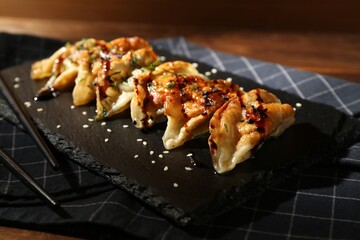 Tasty fried gyoza (dumplings) and chopsticks on wooden table, closeup