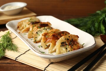 Tasty fried gyoza (dumplings) and chopsticks on wooden table, closeup