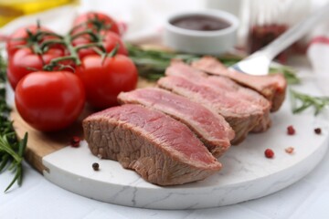 Delicious sliced beef tenderloin with different degrees of doneness, tomatoes and spices on table, closeup