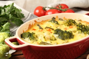 Delicious vegetable casserole and ingredients on wooden table, closeup