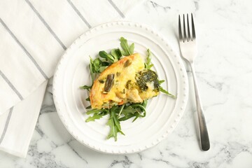 Tasty vegetable casserole, arugula and fork on white marble table, top view