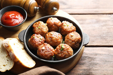 Tasty meatballs with green onion in baking dish served on wooden table