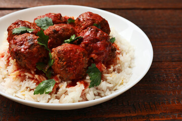 Tasty meatballs with sauce and rice on wooden table, closeup