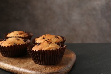 Delicious muffin with chocolate chips on black table, closeup. Space for text