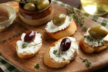 Delicious sandwiches with cream cheese and marinated olives on wooden table
