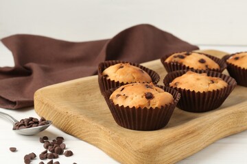Delicious muffin with chocolate chips on white wooden table, closeup