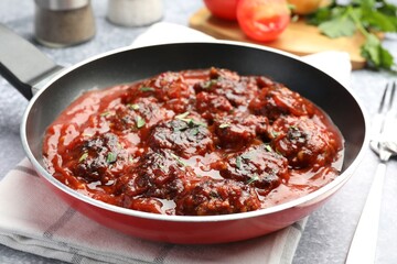 Delicious meatballs with tomato sauce and herbs in served on grey table, closeup