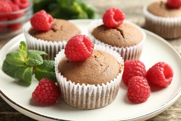Delicious muffins with raspberries and mint on wooden table, closeup