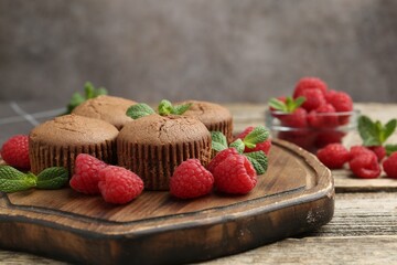 Delicious muffins with raspberries and mint on wooden table, closeup