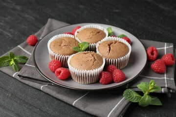 Delicious muffins with raspberries and mint on dark textured table, closeup