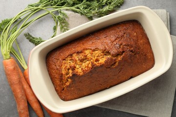 Tasty carrot cake and vegetables on grey textured table, flat lay