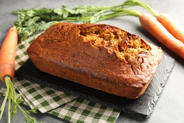 Tasty carrot cake and vegetables on grey textured table, closeup