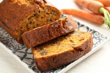 Homemade carrot cake with nuts and vegetables on white wooden table, closeup