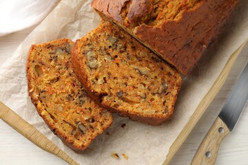 Homemade carrot cake with nuts and knife on white wooden table, top view